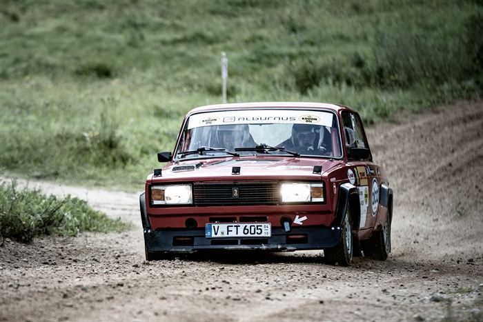 A red rally-prepared Lada driving fast along a gravel track