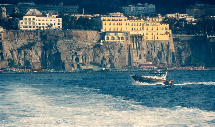 A motorboat crossing in front of clifftop hotels on the Italian coast