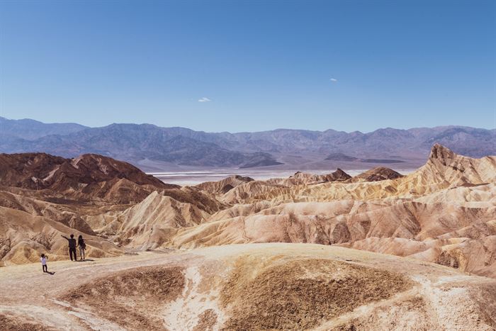 Eroded golden badlands at Zabriskie Point, Death Valley, with visitors standing on a ridge