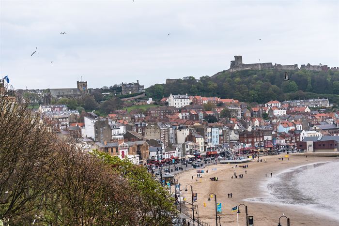 An English seaside town rising from the beach towards a ruined hilltop castle